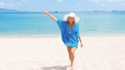 Young beautiful women in the blue tunic on the sunny tropical beach