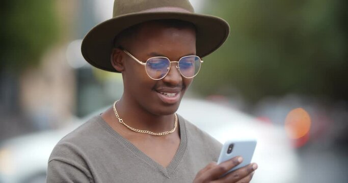 Bokeh shot of happy african young man using mobile phone outdoors