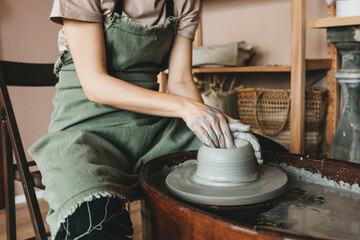 A female craftsman works in a clay workshop on a potter's wheel. The concept of creative people. 