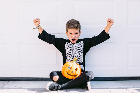 Screaming boy in Halloween outfit with pumpkin