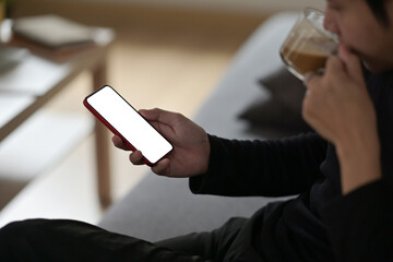 Closed up with male hands using smartphone while drinking coffee, empty screen of smartphone.