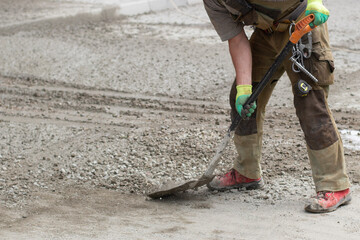 Naklejka premium Work with a shovel at a construction site. A worker throws cement and gravel with a shovel.