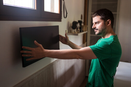 Man installing monitor on wall at home