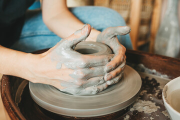 A female craftsman works in a clay workshop on a potter's wheel. The concept of creative people.