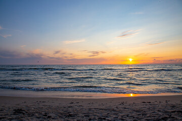 orange sunset with blue sky and dark sandy shore