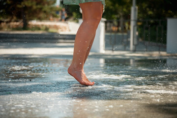 Beautiful female legs in the city fountain. Walking barefoot. Water splashes.
