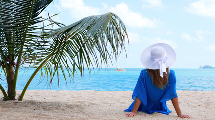 Fototapeta na wymiar Beach vacation. Hot beautiful woman in sunhat and bikini standing with her arms raised to her head enjoying looking view of beach ocean on hot summer day. Photo from Thailand.