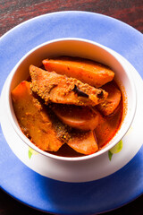 Top view,flat lay of Dum Aloo or Potato gravy or subzi,a popular Indian Punjabi dish in blue bowl. Fried slices of potatoes dipped in thick gravy made of herbs.Traditional cuisine in parties,weddings