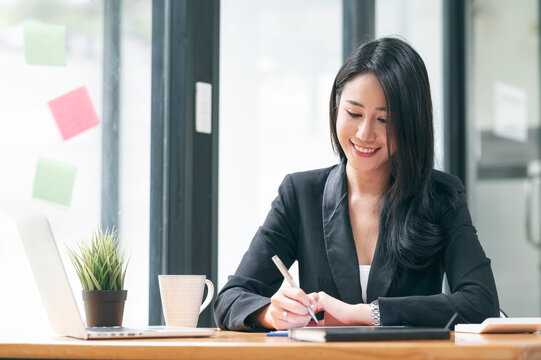 Young beautiful asian businesswoman working with happiness while sitting at the table in office room.