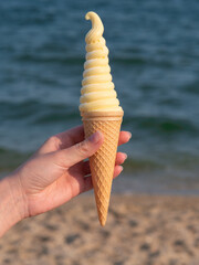 Woman holds ice cream on the beach.
