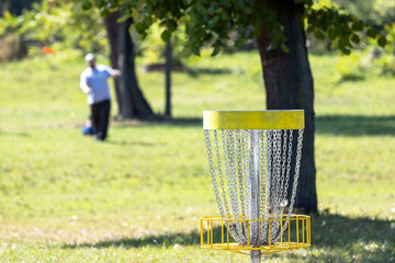 Playing flying disc golf sport game in the park, target basket in focus