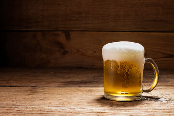 Beer glass with white beer foam on a dark wooden table background