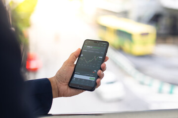 Asian businessman using mobile phone app texting outside the office building