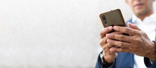 Asian businessman using mobile phone app texting outside the office building