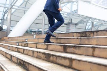 Asian businessman wearing suit jacket running fast upstairs go to work in morning outdoor.