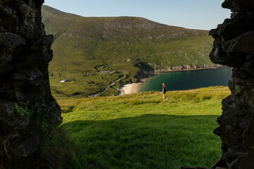 Photo of female traveler in Keem bay Achill Island Ireland through a window of an old building
