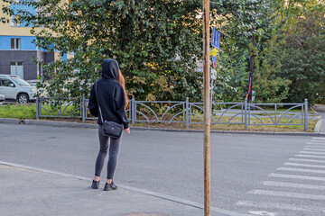 A young woman is waiting for the permission signal of the traffic light