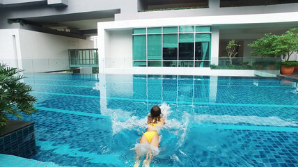 Girl in yellow swim suit relaxing in the big pool. Private propery.