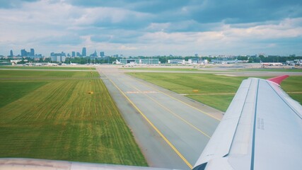 A passenger airplane taxiing runway after landing at the airport. Wing of a flying airplane landing on the runway, view from the airplane window. Beautiful cloudy sky. Travel and air transportation