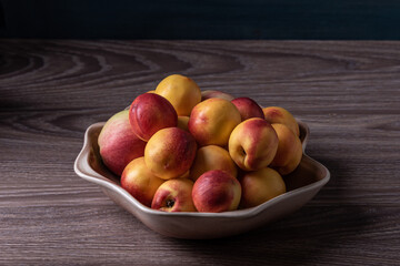 Smooth peaches or nectarines on a plate.
