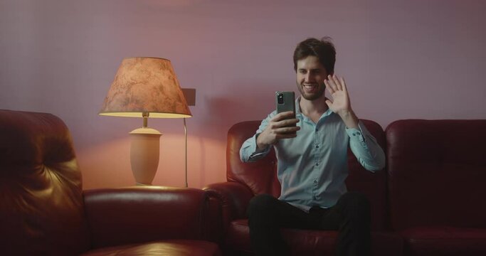 Ragazzo si fa i selfie con lo smartphone mentre &egrave; seduto sul divano di casa