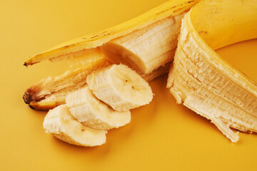 Sliced bananas on yellow background close up, healthy dessert ingredient