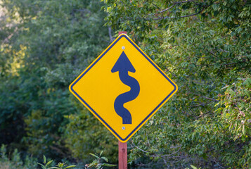 Road sign indicating curves ahead. Selective focus, background and foreground blur.
