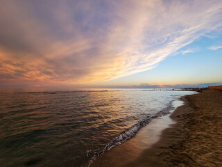 Obraz premium Sunset on the shore of the beach. Multicolored sky, spectacular sunset over the sea with waves on the beach.