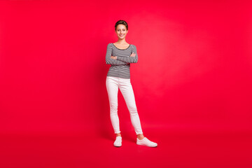 Photo of confident shiny young lady wear striped clothes walking smiling arms crossed isolated red color background