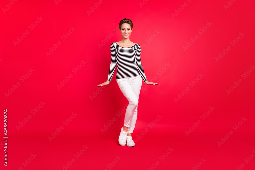 Sticker Photo of charming sweet young lady wear striped clothes walking smiling isolated red color background