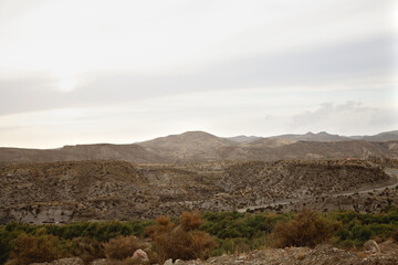 Paisaje de montaña con zonas desérticas. Clima veraniego en la montaña. Carreteras desérticas en mitad de la montaña. Cielos nublados.
