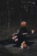 Girl in black halloween costume with a pumpkin instead of a head