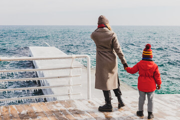 Mother and son on a pier at the sea in winter