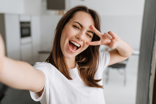 Young white woman smiling and gesturing while taking selfie photo
