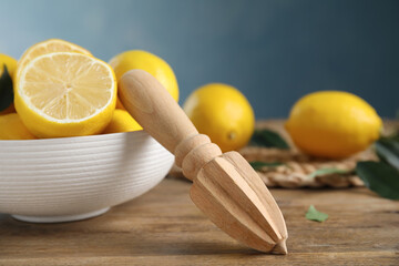 Squeezer with lemons on wooden table, closeup