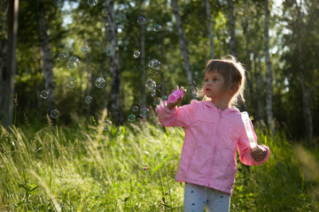  Little girl blowing soap bubbles in the forest