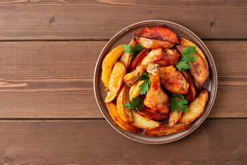 Fried potatoes with chicken legs, on a brown wooden table, horizontal, no people,