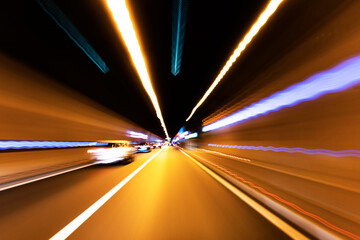 Cars rush through the tunnel in the beams of searchlights. Motion effect.