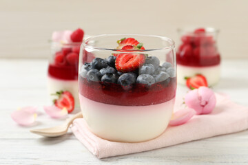 Delicious panna cotta with berries on white wooden table