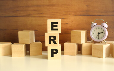 Three wooden cubes stacked vertically on a brown background make up the word ERP.