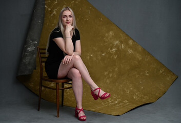beautiful blonde sitting on a chair in the studio in shoes