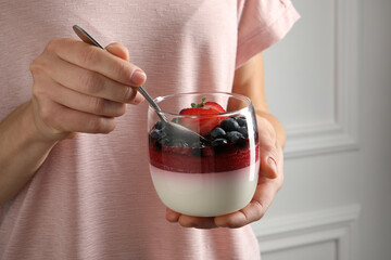 Woman eating delicious panna cotta with berries, closeup