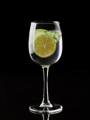 a glass of fresh drinking water and lime. mineral water as a means to quench thirst. on a black background.