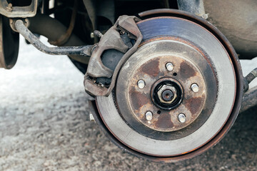 Rusty back car wheel hub with brake disc at tire shop. Car without wheel while replacing on the...