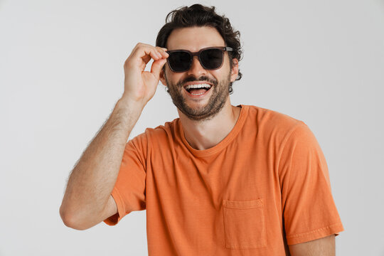 Young brunette man in sunglasses laughing and looking aside
