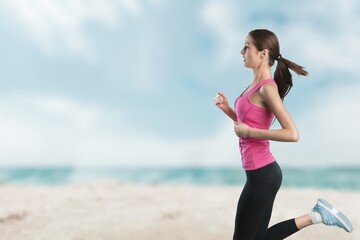 Outdoor shot of young sports woman running along the seashore in morning.