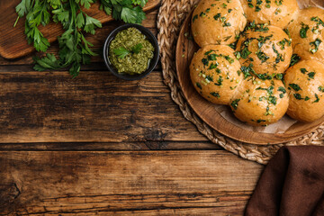 Obraz na płótnie Canvas Traditional pampushka buns with garlic and herbs on wooden table, flat lay. Space for text