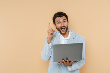 Young white man pointing finger upward while holding his laptop