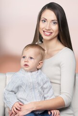 Young beautiful mother lifting and playing with her baby.