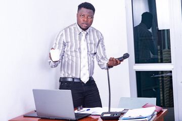 young surprised businessman holding the telephone handset and a cup of coffee.